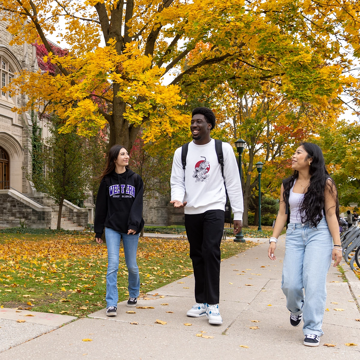 Three students walking on campus in the fall